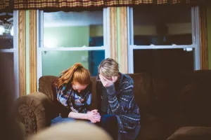 Two people leaning together on a sofa for emotional support