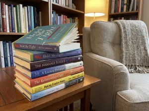 Relationship self-help books stacked beside a chair