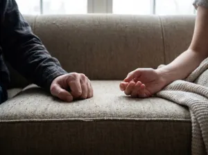 Couple seated on opposite sides of a sofa, illustrating a pursue-withdraw pattern
