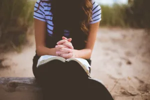 Person seated with hands clasped while listening