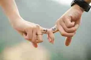 Couple linking little fingers to show connection and commitment