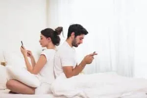 couple sitting back to back on their cell phones Couple sitting back-to-back while looking at their phones