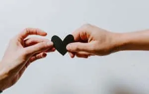 Two hands offering pieces of a heart, representing emotional connection