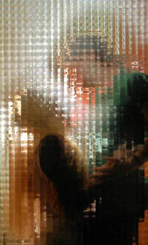 Silhouettes of two people embracing behind patterned glass