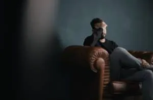 Man seated with his head resting on his hand during emotional distress